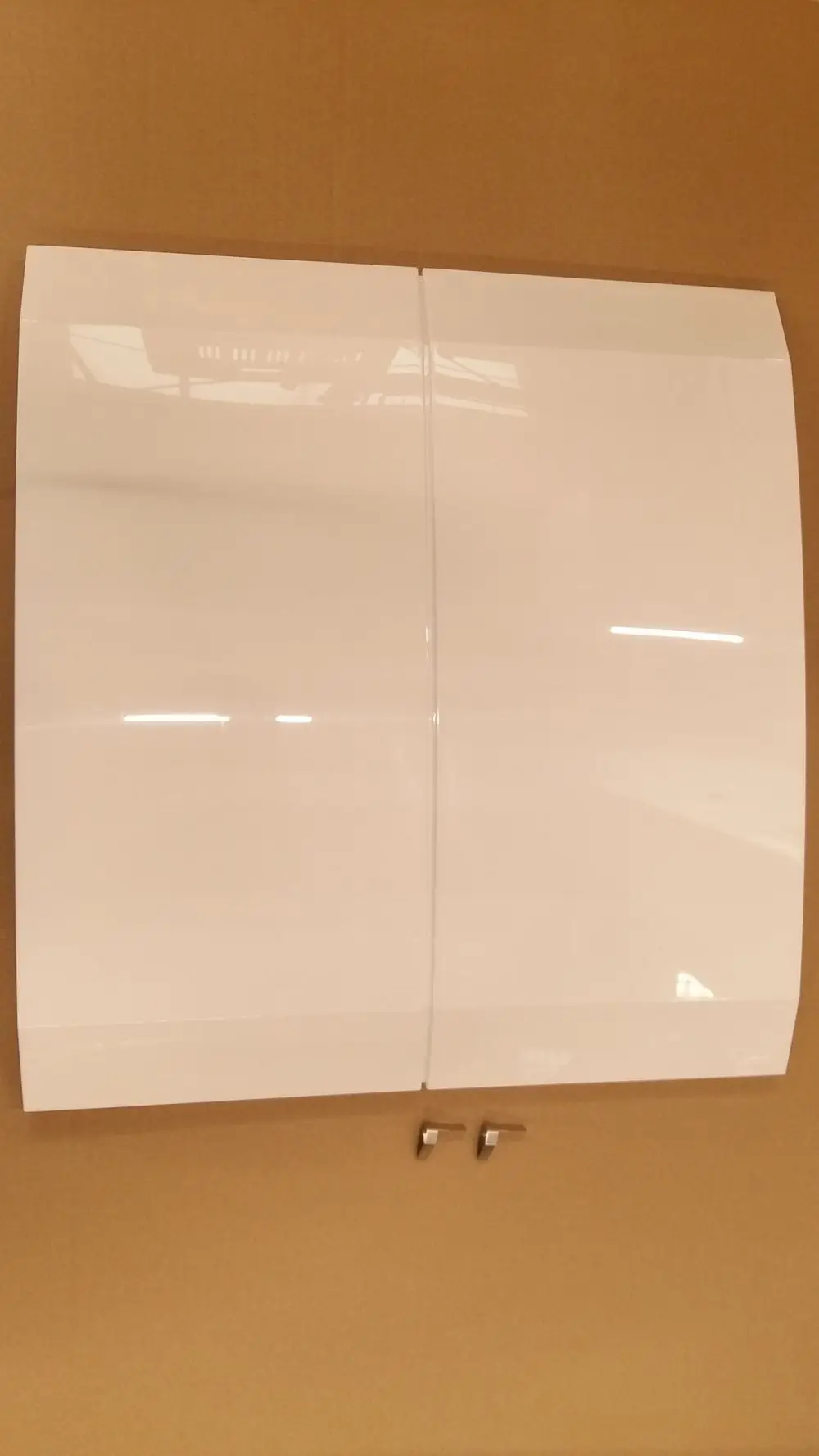 Weiße, glänzende Vorderwand von Remeha mit gerader Kante und einer nahtlosen Verbindung in der Mitte, montiert auf einer braunen Verpackungsfläche.